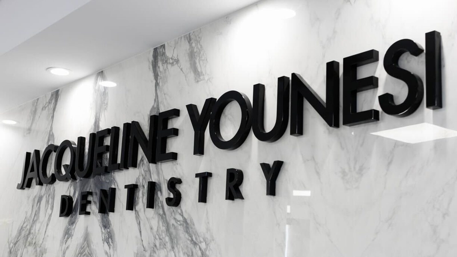 Jacqueline Younesi Dentistry lettering mounted on the marble wall inside the practice