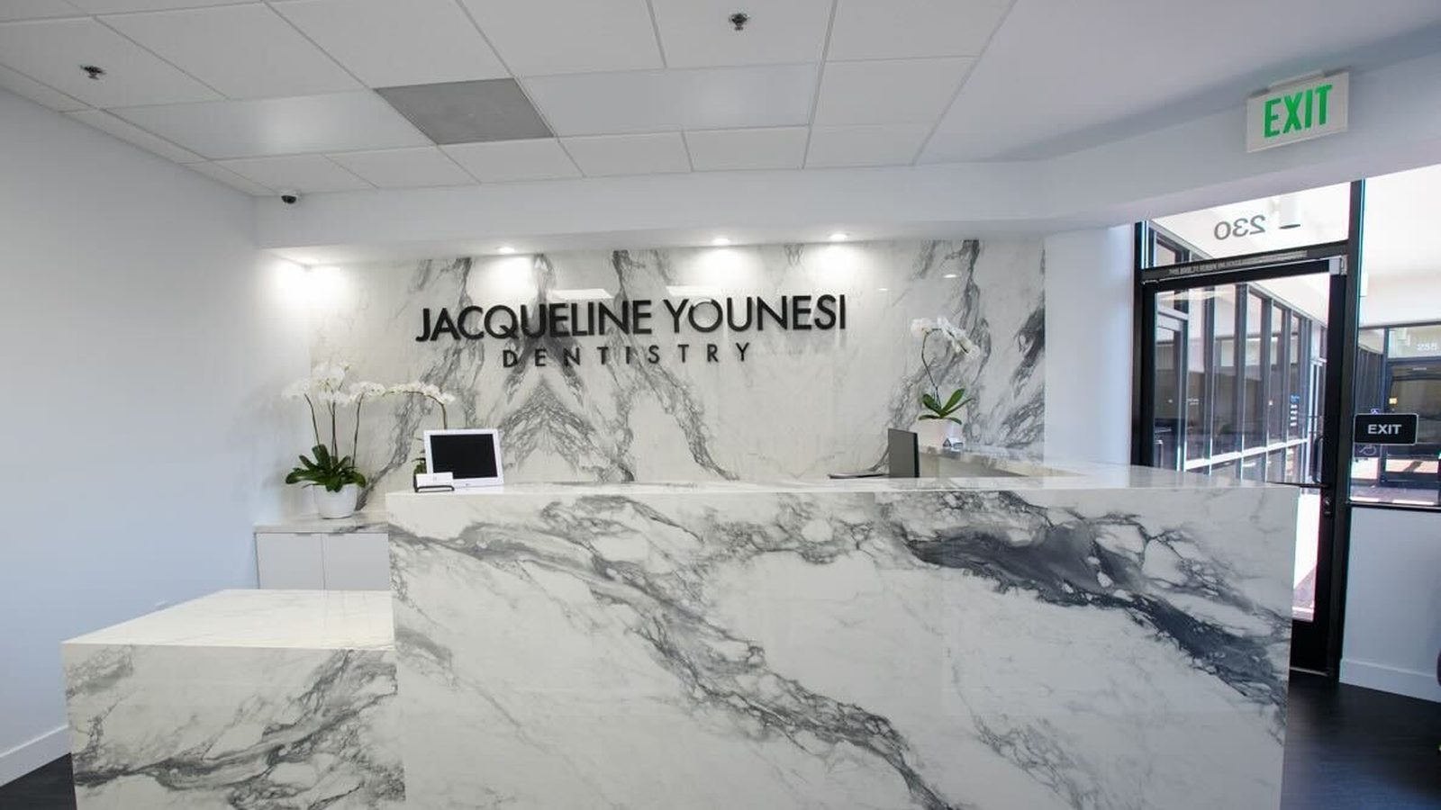 The marble reception desk and signage in the entrance of Jacqueline Younesi Dentistry