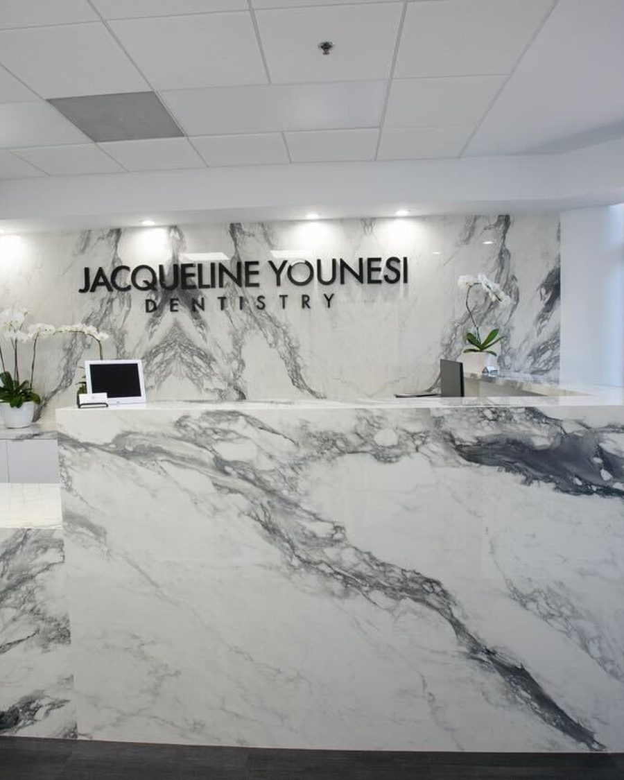The marble reception desk and signage inside Jacqueline Younesi Dentistry